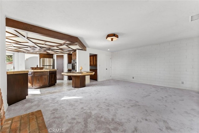 unfurnished living room featuring brick wall and light carpet