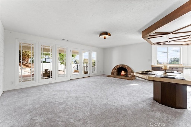 interior space featuring french doors, a fireplace, carpet floors, and a textured ceiling