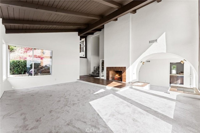 unfurnished living room with wood ceiling, high vaulted ceiling, carpet, and beamed ceiling