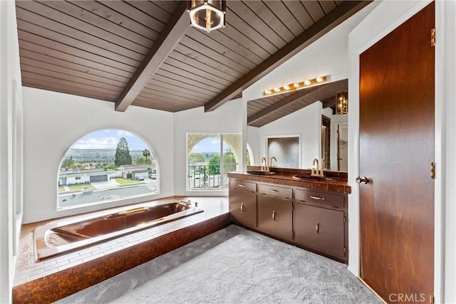 bathroom featuring lofted ceiling with beams, vanity, tiled tub, and wood ceiling