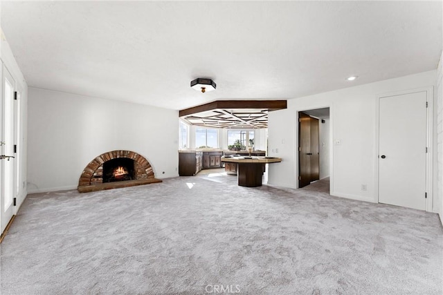 unfurnished living room featuring carpet floors and a brick fireplace