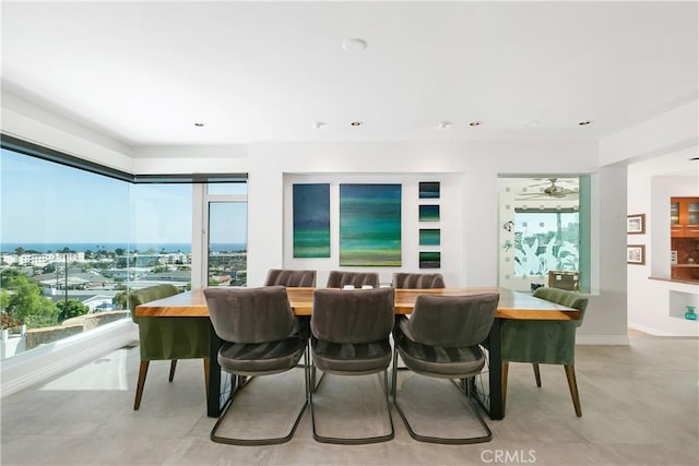 dining space with baseboards, recessed lighting, and a water view