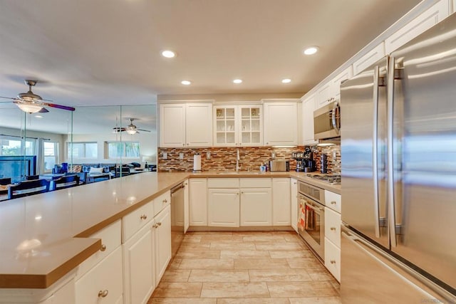 kitchen with hanging light fixtures, white cabinetry, appliances with stainless steel finishes, and decorative backsplash