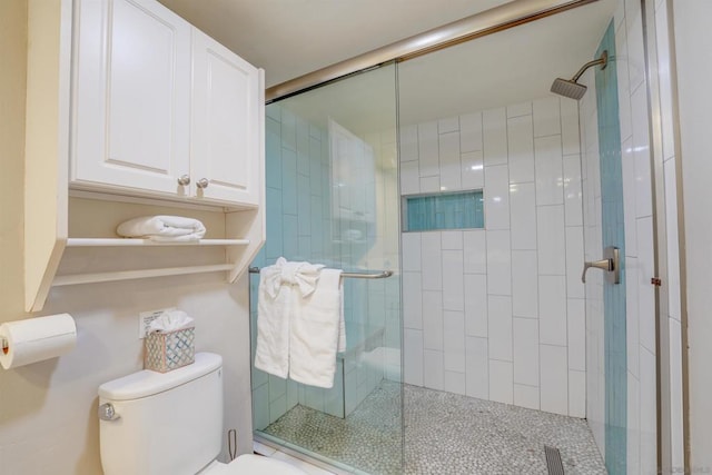 bathroom featuring toilet and a shower with shower door