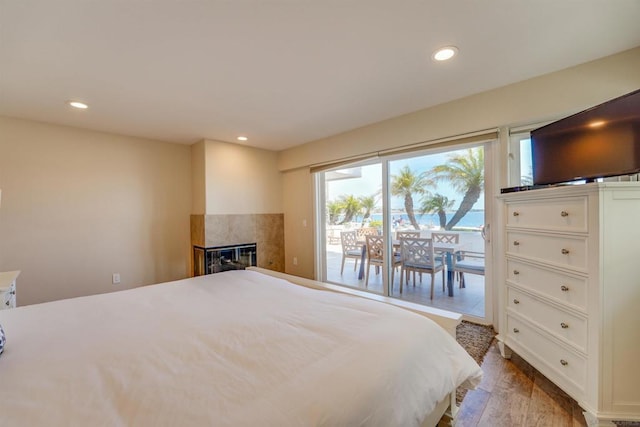 bedroom featuring hardwood / wood-style flooring, access to outside, and a fireplace