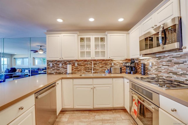 kitchen with sink, ceiling fan, stainless steel appliances, decorative backsplash, and white cabinets