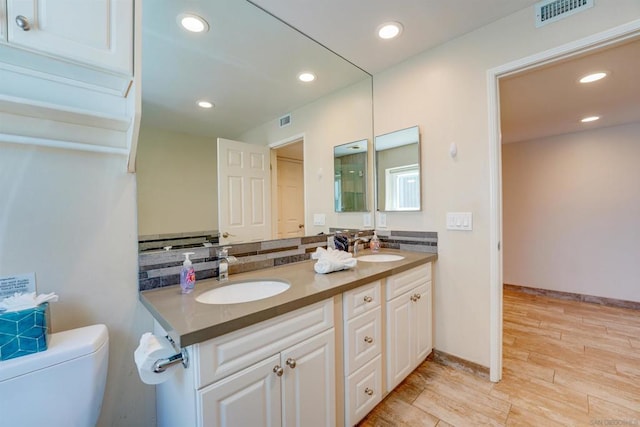 bathroom featuring tasteful backsplash, vanity, toilet, and wood-type flooring