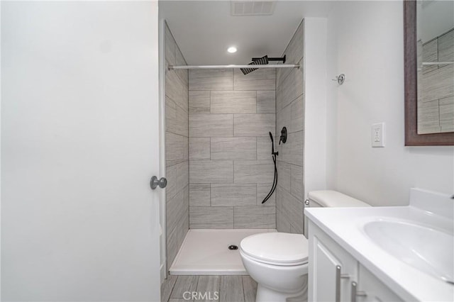 bathroom featuring vanity, toilet, wood-type flooring, and a tile shower