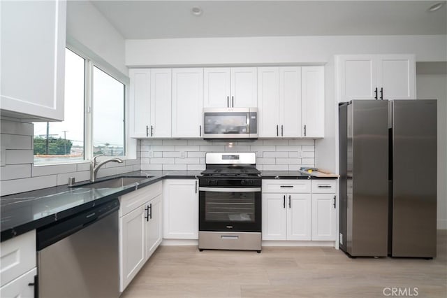 kitchen with sink, white cabinetry, tasteful backsplash, light hardwood / wood-style flooring, and appliances with stainless steel finishes