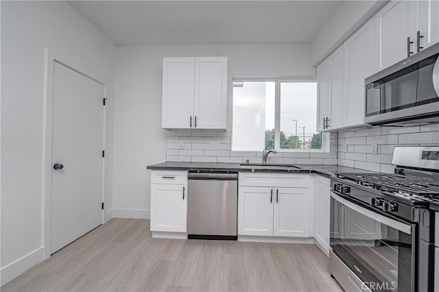 kitchen featuring sink, decorative backsplash, stainless steel appliances, and white cabinets