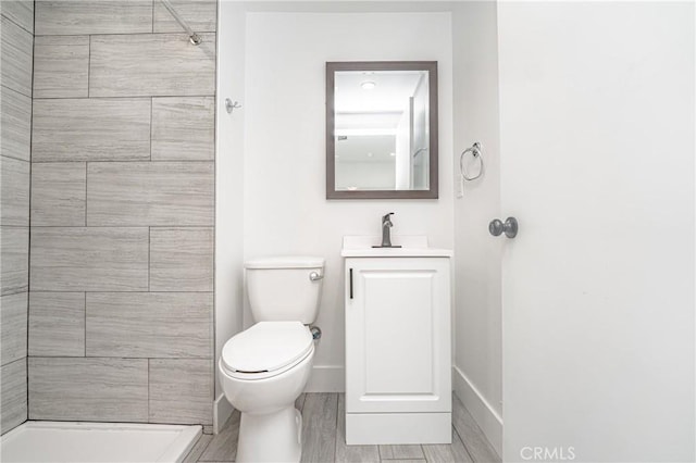 bathroom with vanity, tiled shower, and toilet