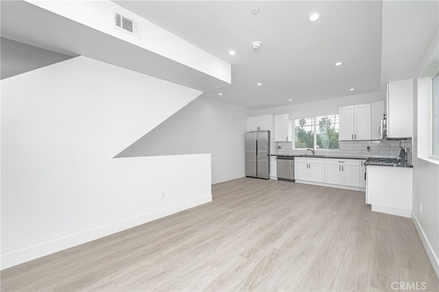 kitchen with sink, light hardwood / wood-style flooring, backsplash, stainless steel appliances, and white cabinets