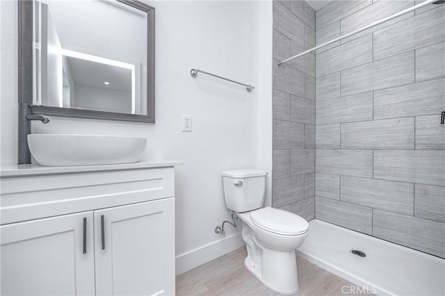 bathroom featuring vanity, toilet, and a tile shower