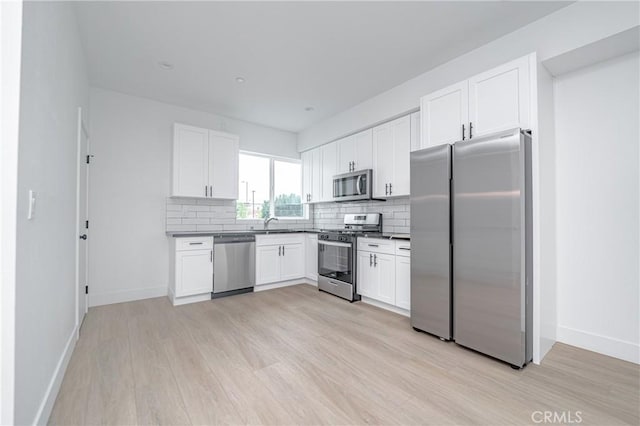 kitchen with backsplash, light hardwood / wood-style flooring, white cabinets, and appliances with stainless steel finishes