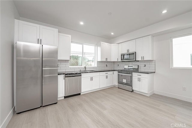 kitchen featuring appliances with stainless steel finishes, sink, white cabinets, and decorative backsplash