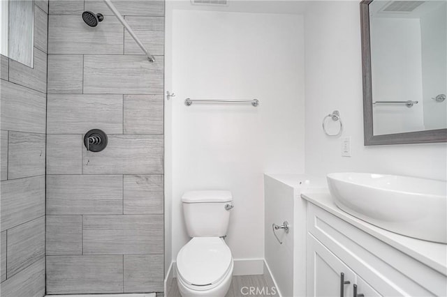 bathroom with vanity, toilet, and a tile shower