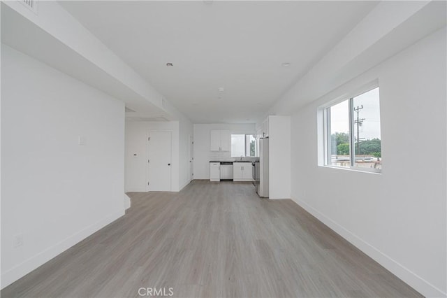 unfurnished living room featuring sink and light hardwood / wood-style floors