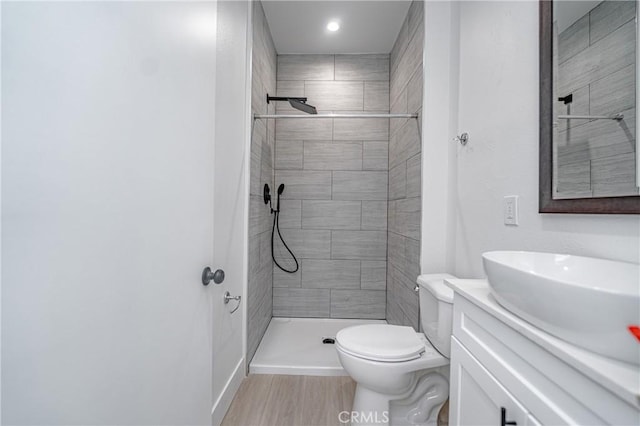 bathroom featuring tiled shower, vanity, and toilet