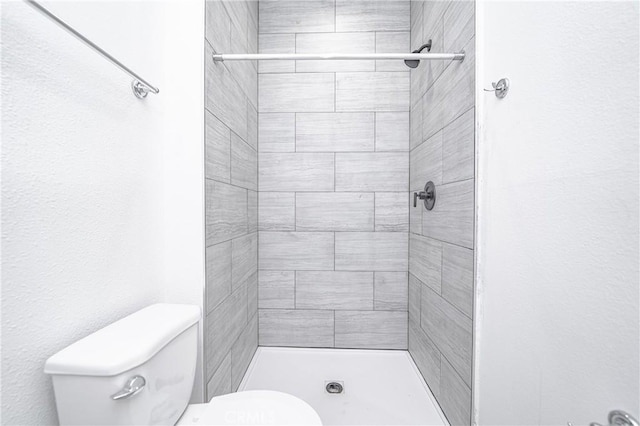 bathroom featuring toilet and tiled shower