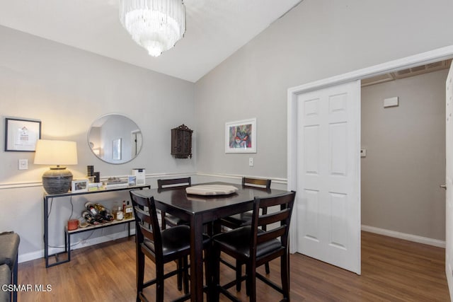 dining room with lofted ceiling, hardwood / wood-style floors, and a chandelier