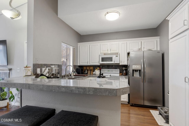 kitchen with white cabinets, white appliances, and kitchen peninsula