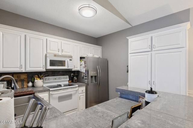 kitchen featuring white appliances, sink, decorative backsplash, and white cabinets