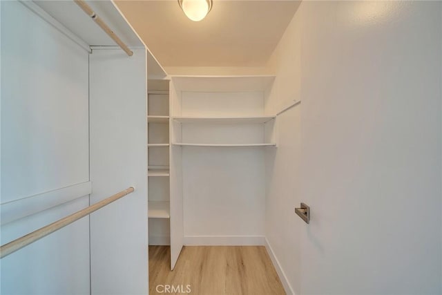 walk in closet with light hardwood / wood-style floors