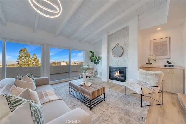 living room with a large fireplace, wooden ceiling, light hardwood / wood-style floors, and vaulted ceiling with beams