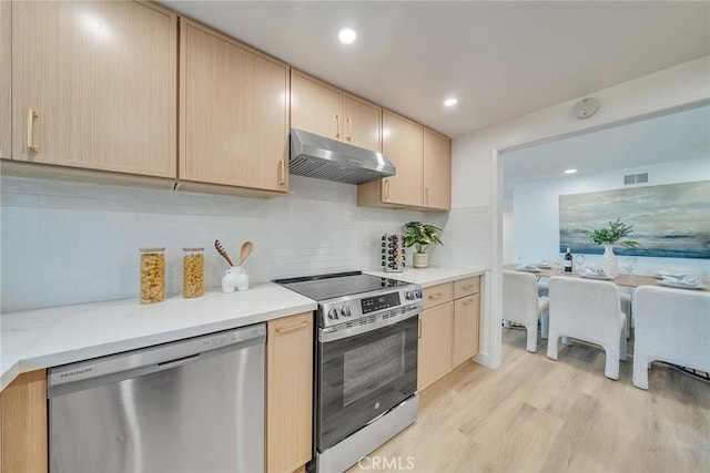 kitchen with tasteful backsplash, appliances with stainless steel finishes, light wood-type flooring, and light brown cabinets