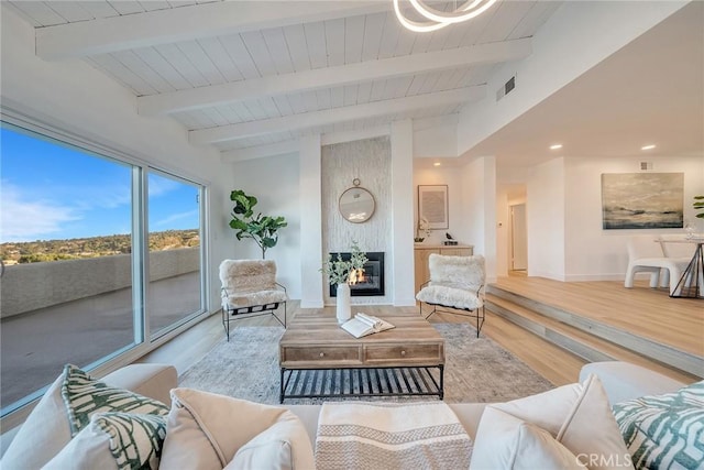 living room with hardwood / wood-style floors, vaulted ceiling with beams, and a large fireplace