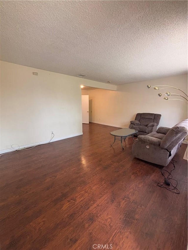 unfurnished living room with dark wood-type flooring and a textured ceiling