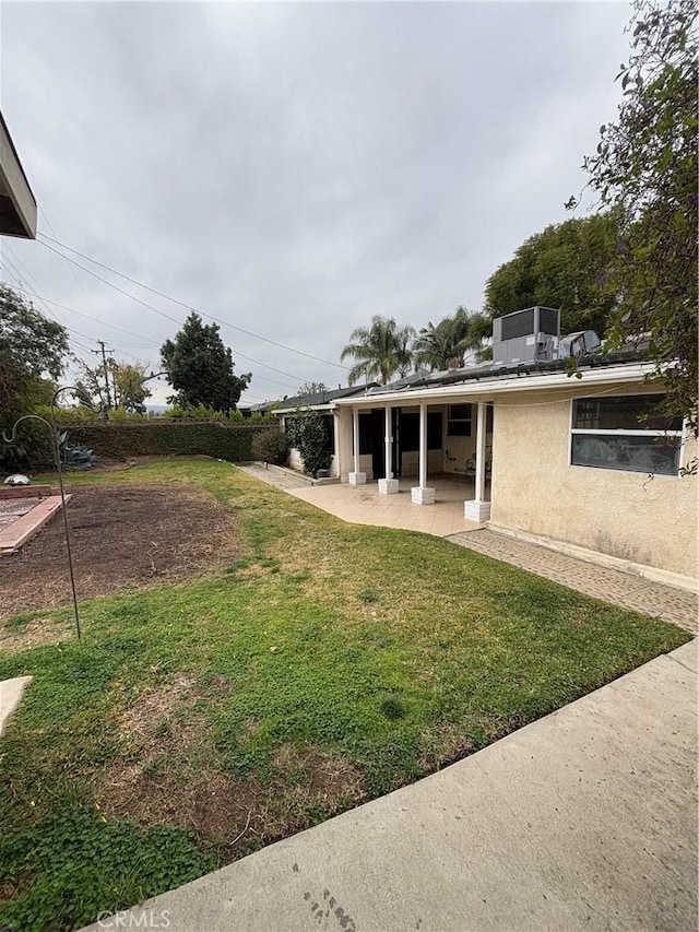 view of yard with central AC and a patio