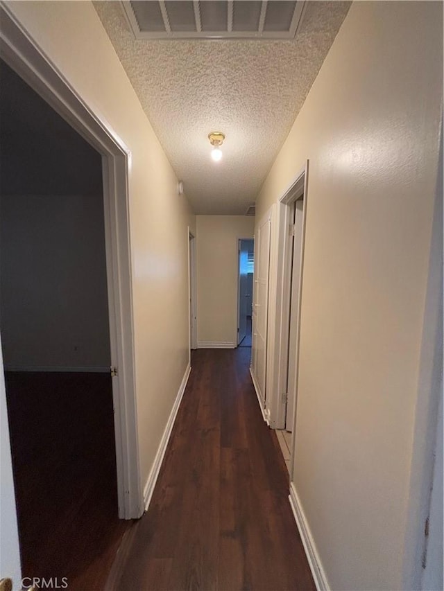 hall featuring dark wood-type flooring and a textured ceiling