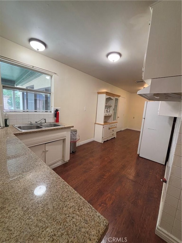 kitchen featuring sink, light stone counters, white cabinets, dark hardwood / wood-style flooring, and decorative backsplash