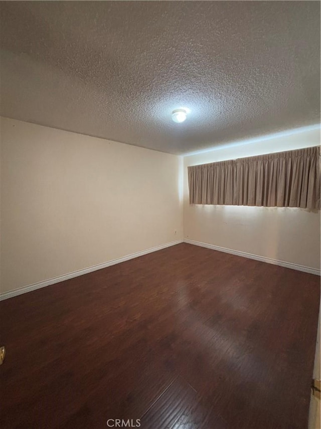 unfurnished room featuring dark hardwood / wood-style flooring and a textured ceiling