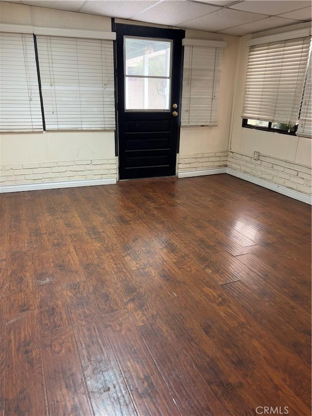 interior space with a drop ceiling and hardwood / wood-style flooring