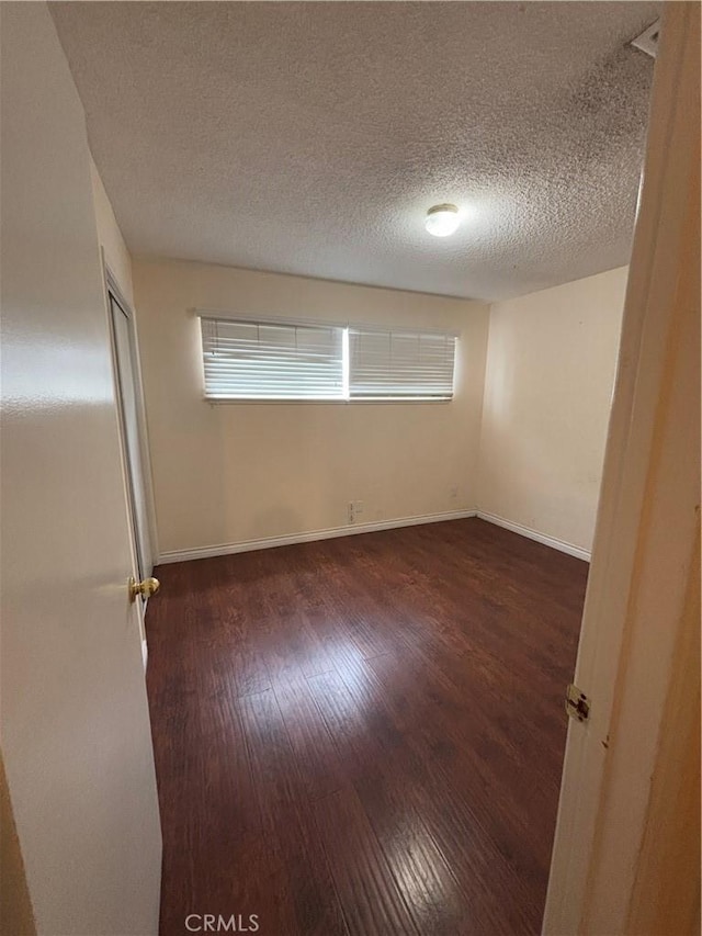 spare room with dark hardwood / wood-style floors and a textured ceiling