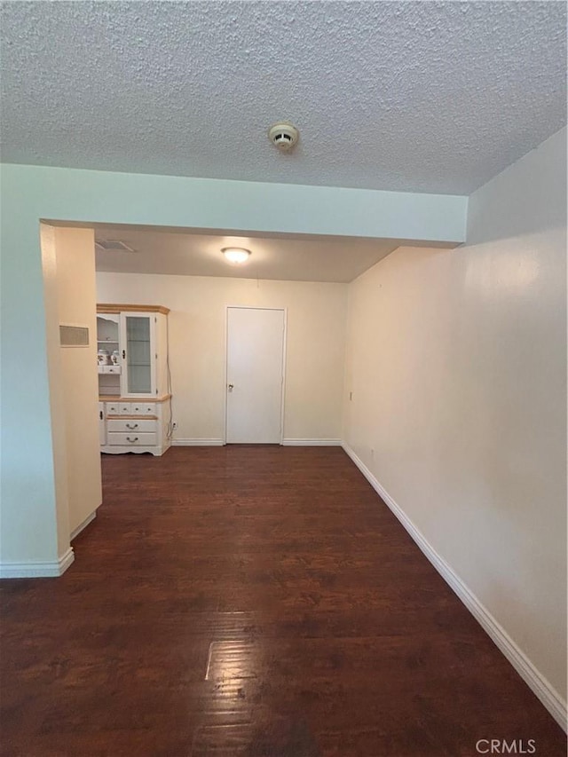 spare room featuring dark wood-type flooring and a textured ceiling