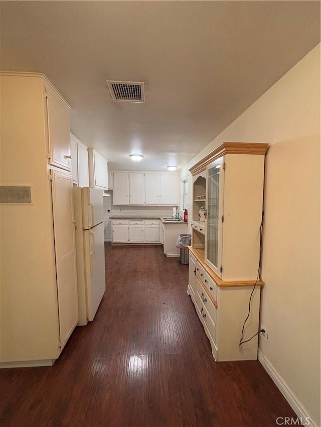 kitchen featuring white refrigerator, dark hardwood / wood-style flooring, sink, and white cabinets