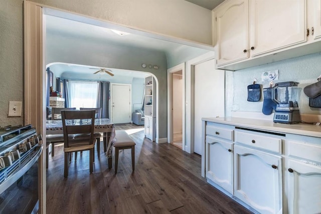 kitchen with ceiling fan, dark hardwood / wood-style flooring, range with gas stovetop, and white cabinets