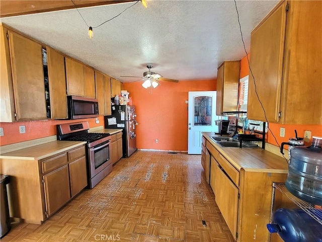 kitchen with ceiling fan, stainless steel appliances, a textured ceiling, and light parquet floors