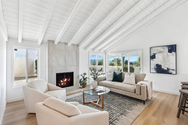 living room with a tiled fireplace, vaulted ceiling with beams, wood ceiling, and light hardwood / wood-style floors