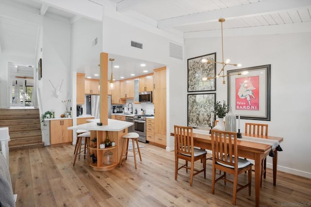 dining space with sink, a notable chandelier, light hardwood / wood-style flooring, and lofted ceiling with beams