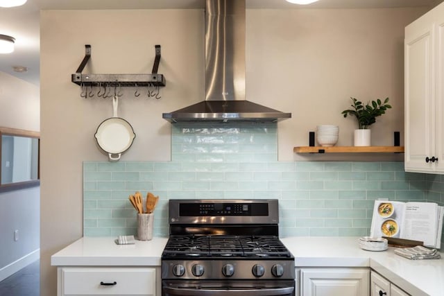 kitchen featuring tasteful backsplash, white cabinets, range hood, and stainless steel gas range oven