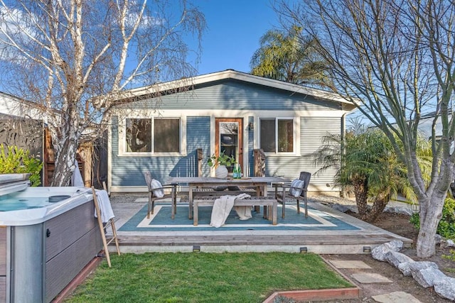 back of house with a hot tub and a wooden deck