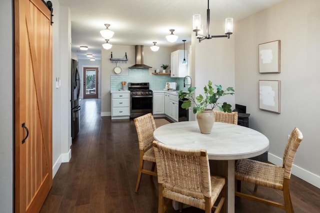 dining room featuring a barn door, dark wood-type flooring, and a notable chandelier