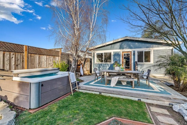 rear view of property with a wooden deck, an outbuilding, and a hot tub