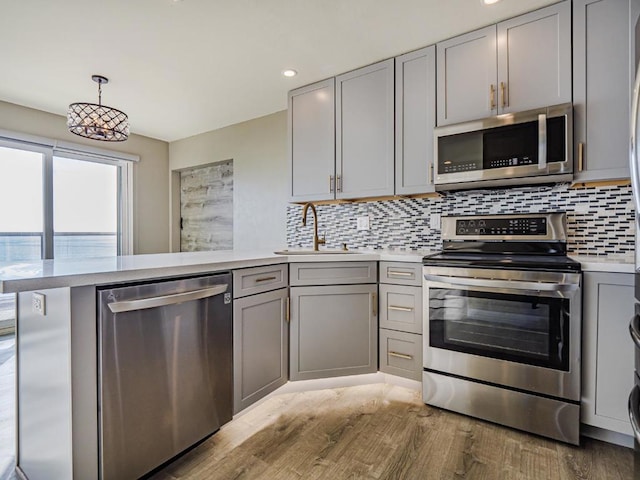 kitchen with appliances with stainless steel finishes, kitchen peninsula, and gray cabinetry