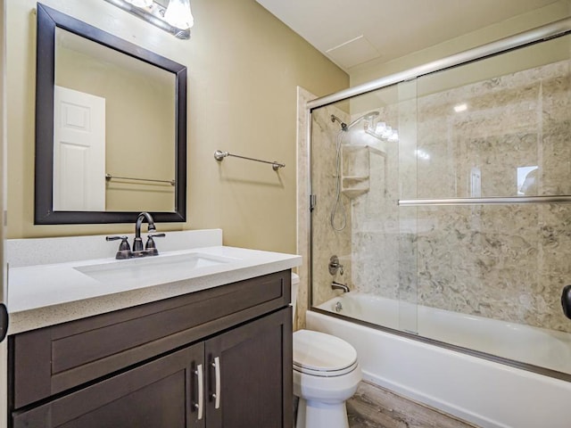 full bathroom featuring vanity, hardwood / wood-style flooring, bath / shower combo with glass door, and toilet