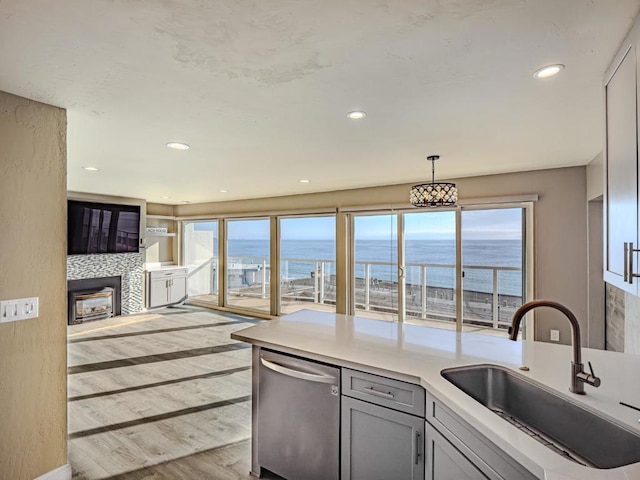 kitchen featuring gray cabinets, pendant lighting, sink, stainless steel dishwasher, and light hardwood / wood-style floors